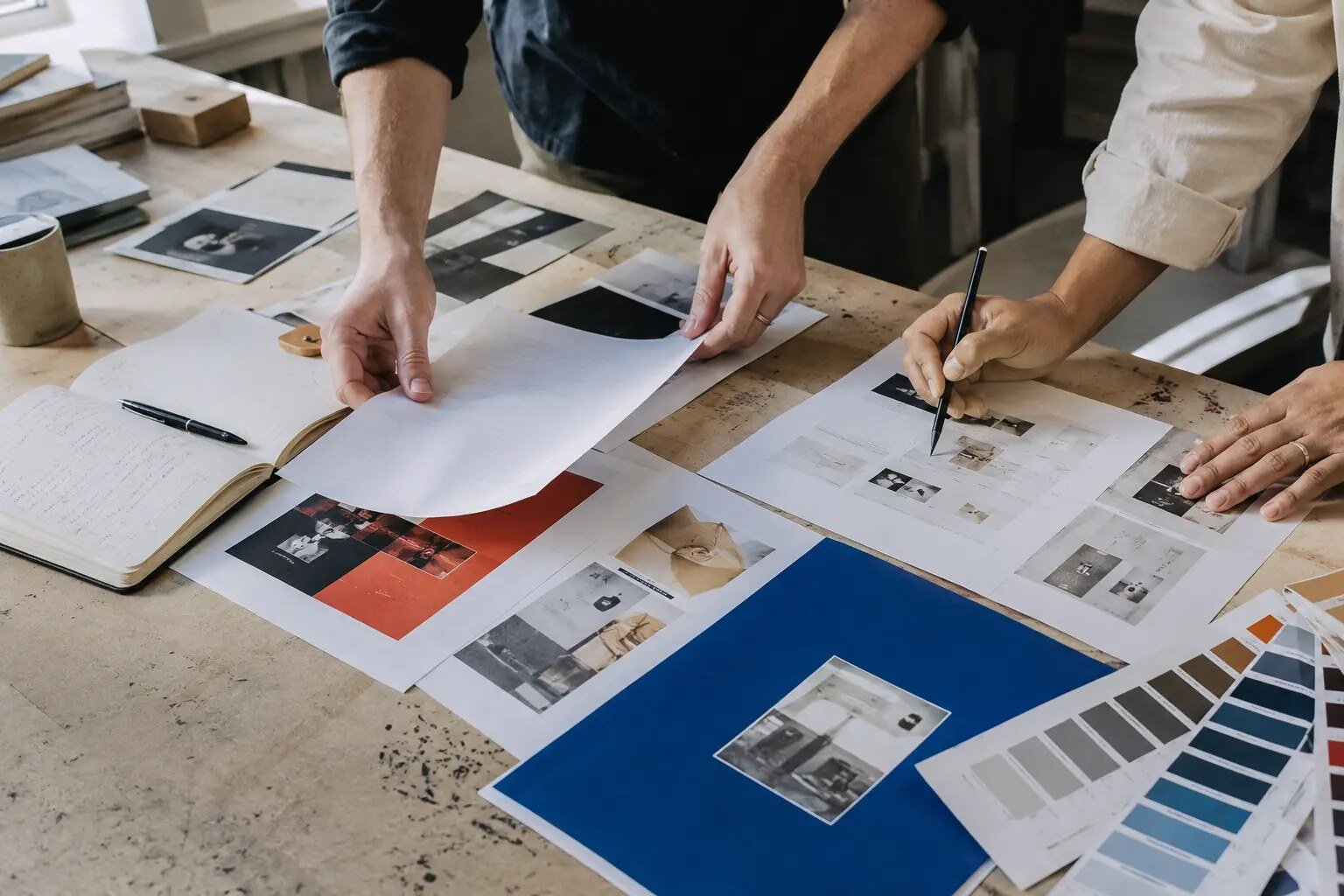 Creative professionals arranging printed brand materials on a studio table